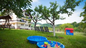 Guests can enjoy an outdoor space with a lawn, swing set, and play area featuring two boats and a wooden structure.