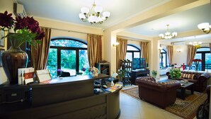 A spacious living room with a large window, a fireplace, and a comfortable seating area. - Pensiunea Toscana (Brasov)
