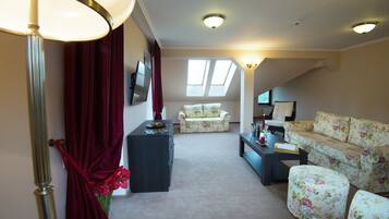 A living room with a sofa, a chair, a coffee table, and a lamp. There are windows and a ceiling light.