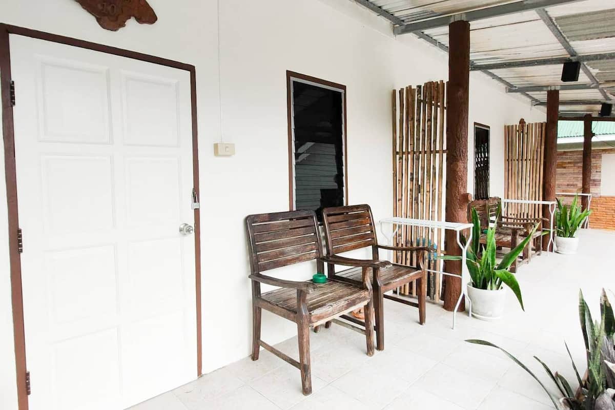 A covered porch with a wooden bench, a white door, and a wooden fence.