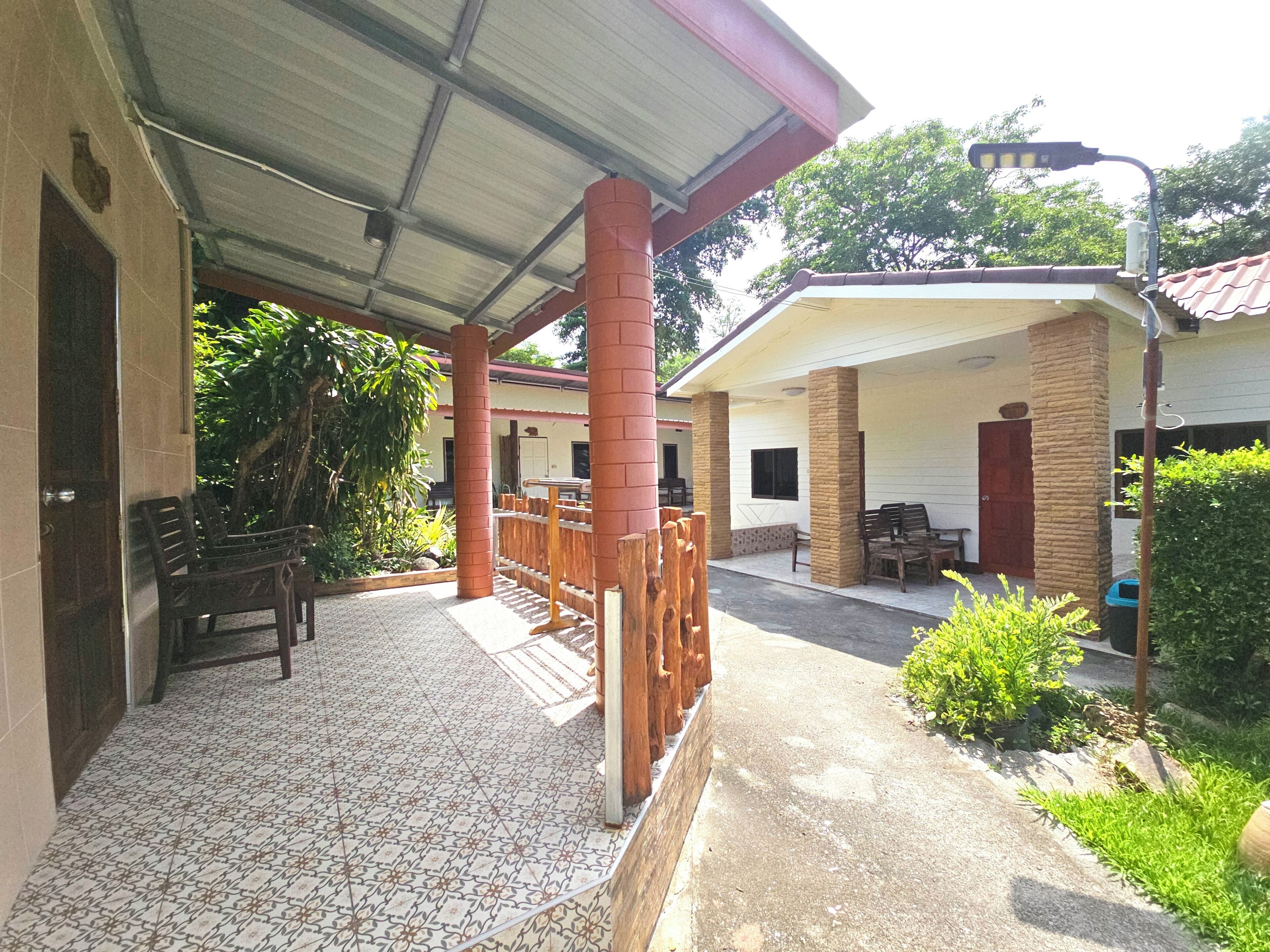 A covered outdoor area with tiled flooring, wooden furniture, and a brick pillar.