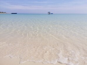 A beach with clear shallow water and a distant boat. - Samet Bellhouse (Rayong)