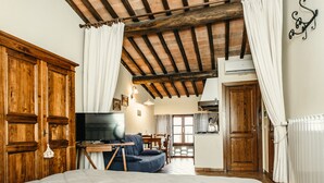 A bedroom with a large bed, wooden wardrobe, and a television. - Casa di Campagna in Toscana (Sovicille)