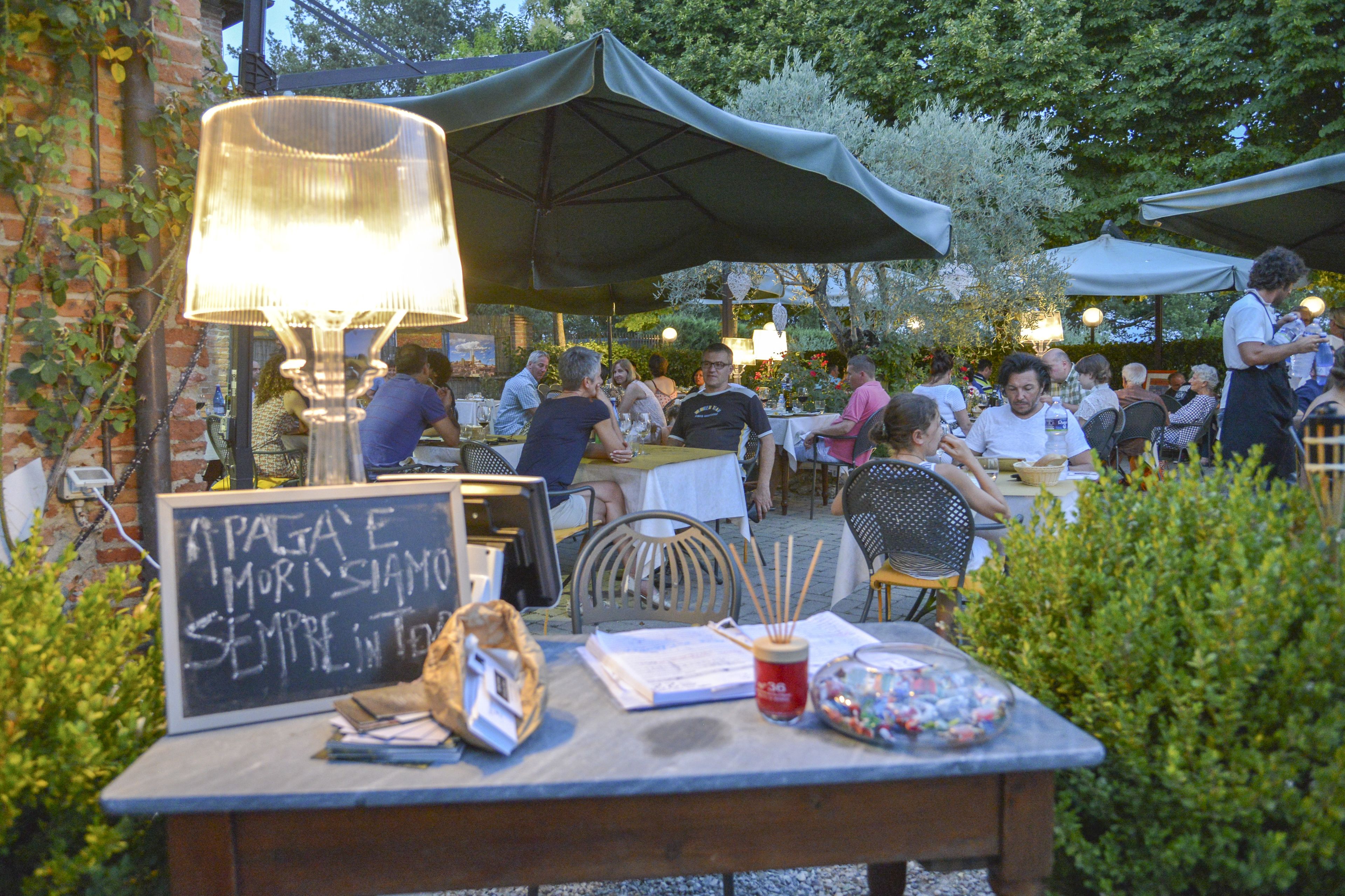 An outdoor dining area with tables and chairs, umbrellas, and a chalkboard sign.