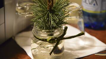 A glass jar with a sprig of greenery, placed on a white napkin on a wooden surface.