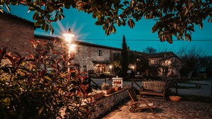 A stone courtyard with a bench, a table, and a lamp post. - Casa di Campagna in Toscana (Sovicille)