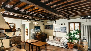 A rustic living room with exposed wooden beams, a wooden table, a sofa, and a potted plant. - Casa di Campagna in Toscana (Sovicille)