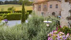 A rustic stone building with a garden in front, a clear view of the countryside, and a lamp post. - Casa di Campagna in Toscana (Sovicille)