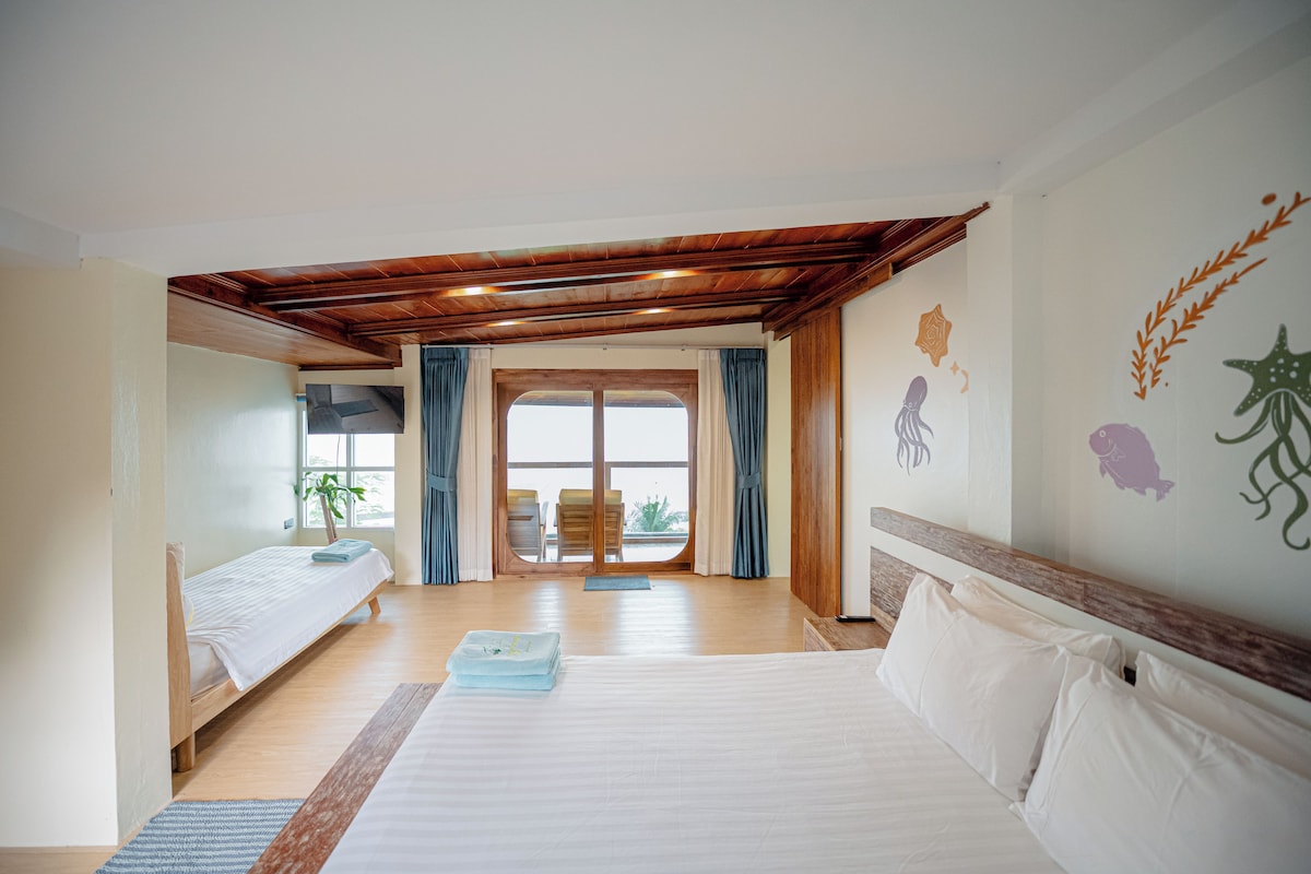 A hotel room with a large bed, a smaller bed, a window with curtains, and a view of the outdoors.