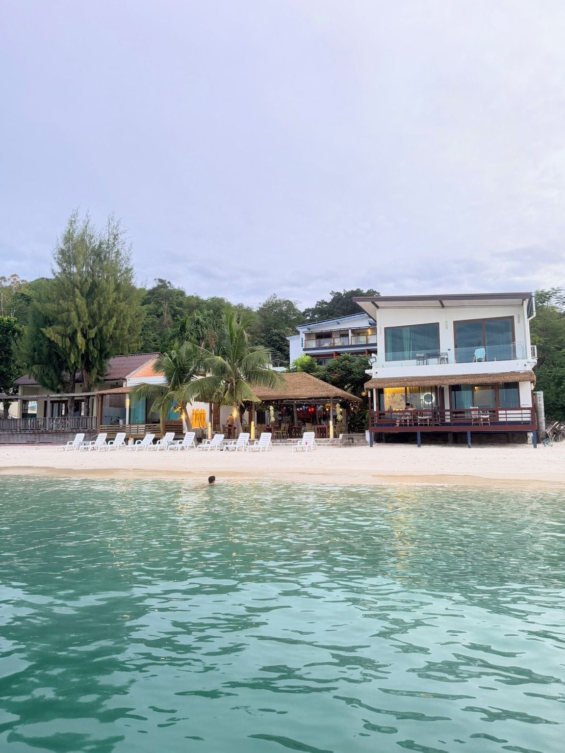 A beachfront property with a pool, lounge chairs, and a restaurant.