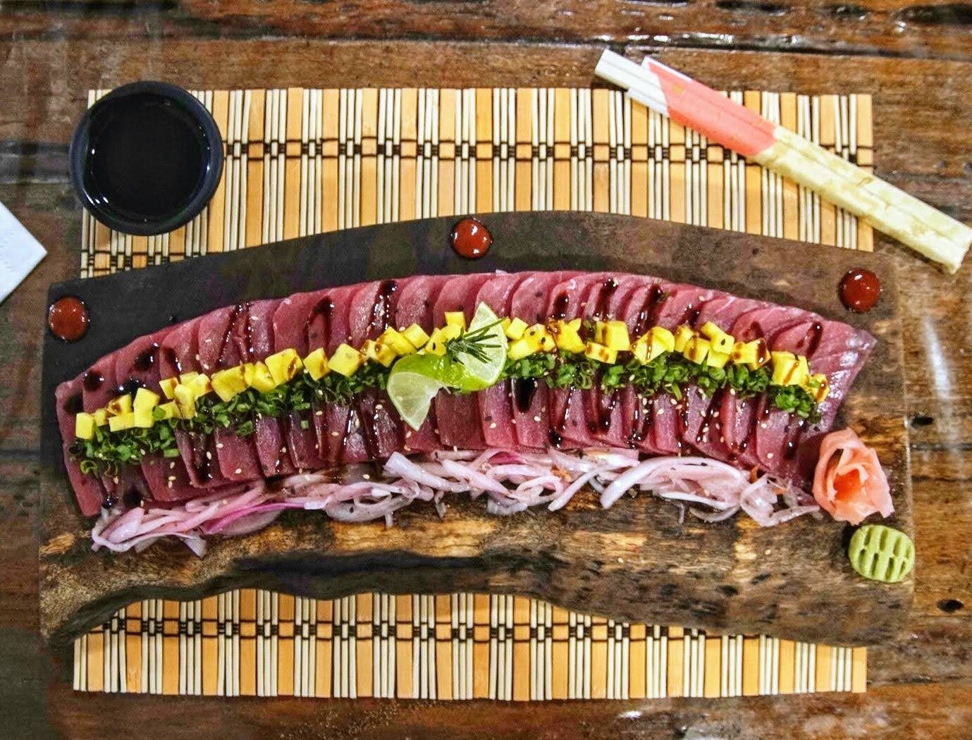 A sushi platter with various toppings and condiments on a wooden board.