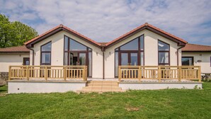 A two-story house with a balcony, a front door, and a small porch. - Stoneleigh Village (Sidmouth)