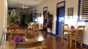 A dining area with wooden tables and chairs, a ceiling fan, and a blue door. - La Posada Azul (San Juan del Sur)