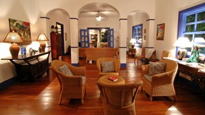 A spacious lobby with wicker furniture, a central seating area, and a view into the dining area. - La Posada Azul (San Juan del Sur)