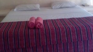 Una habitación de hotel con una cama, almohadas y toallas dobladas sobre la cama.