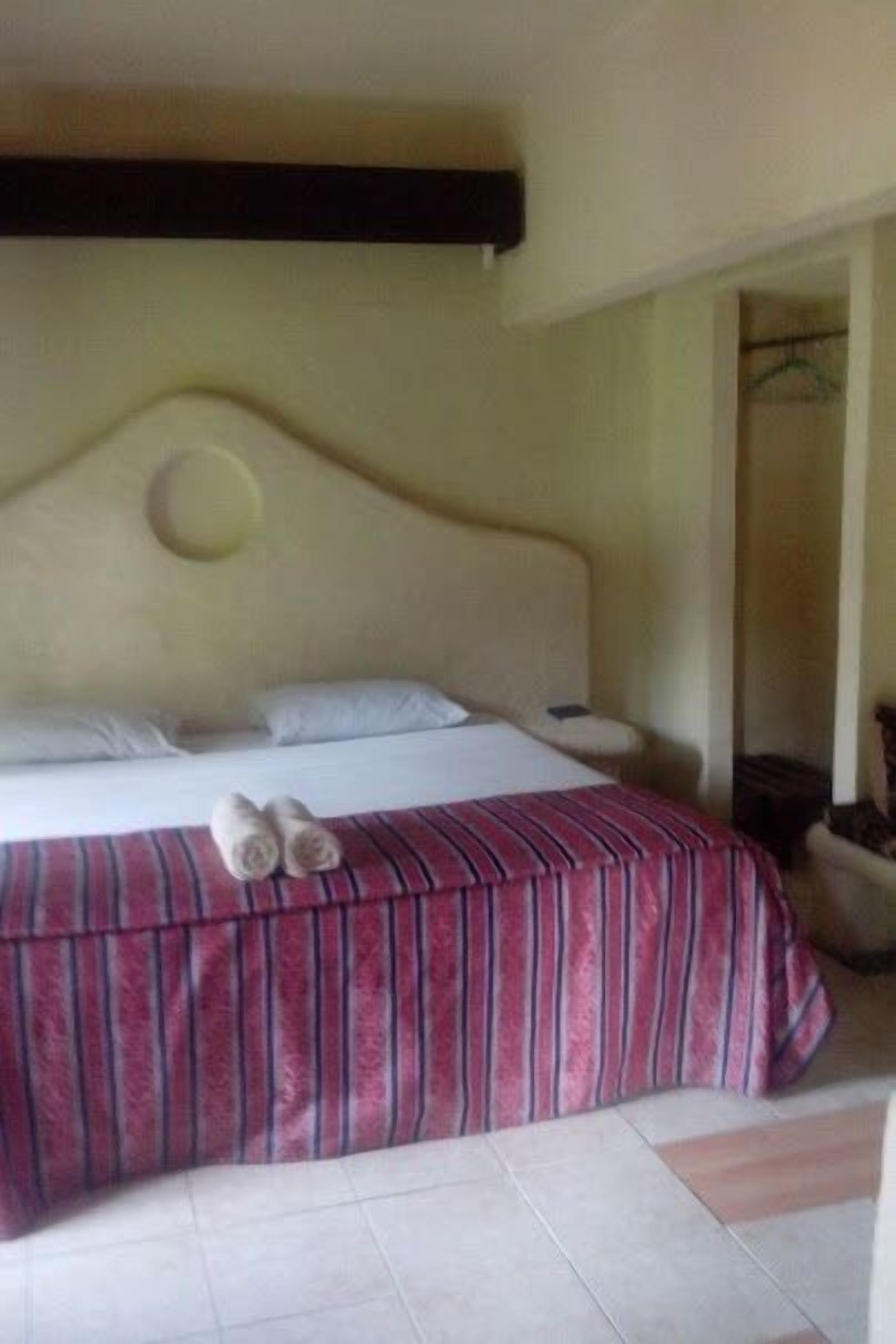Una habitación de hotel con una cama, un edredón a rayas y dos toallas sobre la cama.