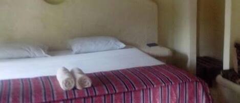 Una habitación de hotel con una cama, un edredón a rayas y dos toallas sobre la cama.