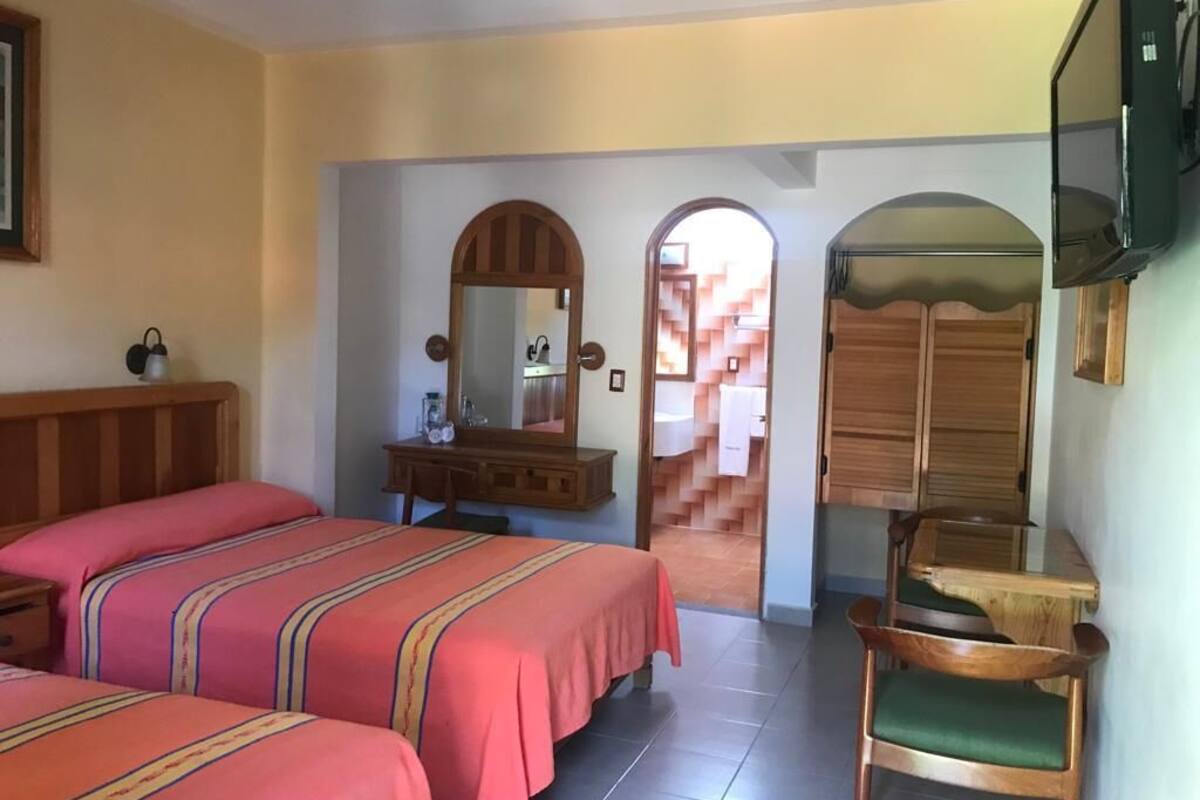 A hotel room with two beds, a wooden dresser, a chair, and a television.