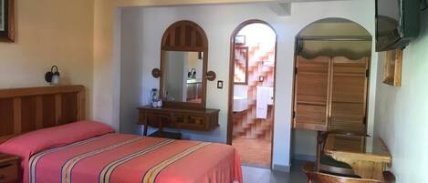 A hotel room with two beds, a wooden dresser, a chair, and a television.