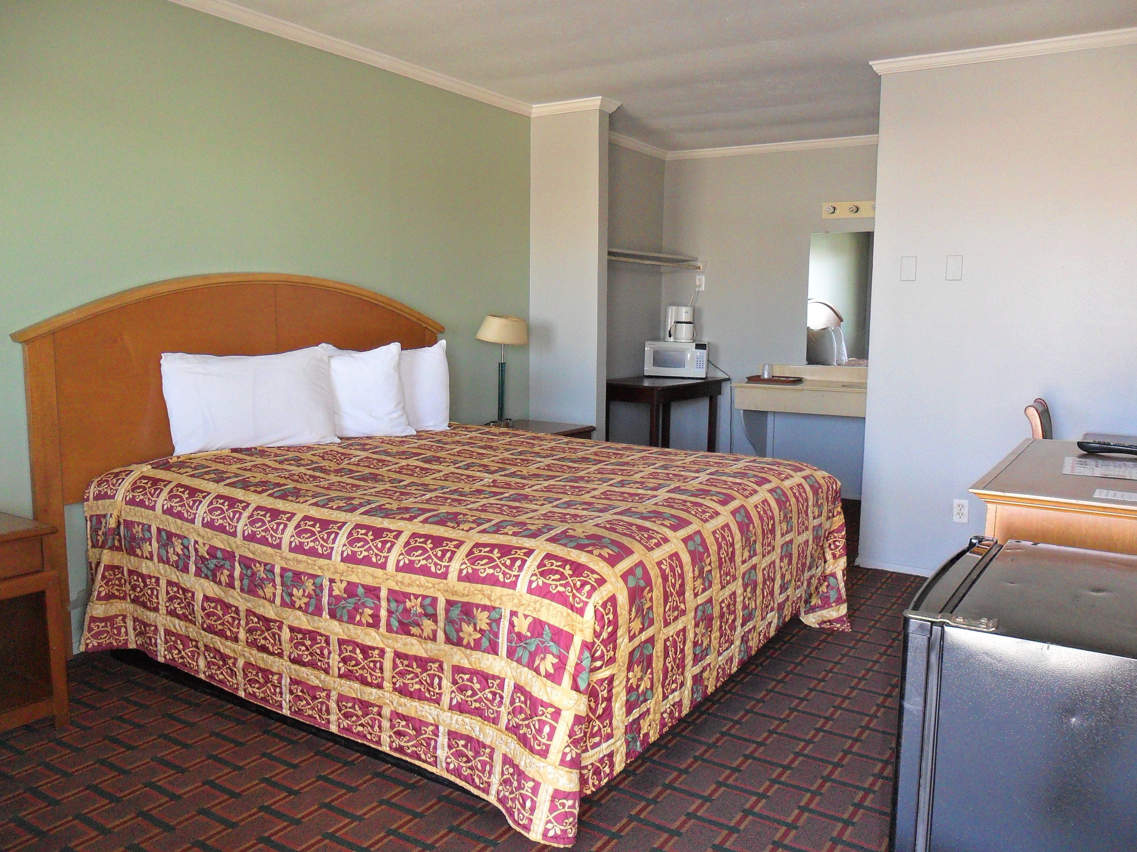 Une chambre d’hôtel équipée d’un lit, d’un bureau, d’un four à micro-ondes et d’un réfrigérateur.