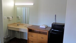 A bathroom with a sink, mirror, towel rack, and a black refrigerator. - A OK Motel (Muenster)