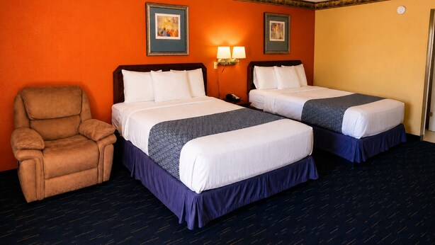 A hotel room with two beds, a chair, and two wall-mounted lamps. - Country Inn Sterling (Sterling)
