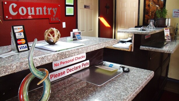 A hotel reception desk with a 'Country Inn' sign, a 'No Personal Checks' sign, and a 'Please Declare Pets' sign. - Country Inn Sterling (Sterling)