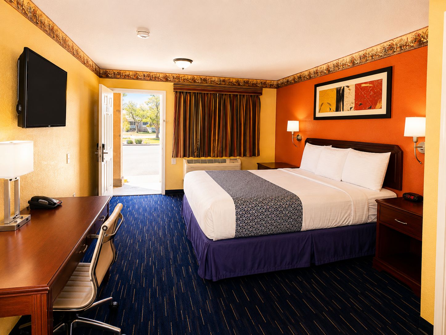 Ein Hotelzimmer mit Bett, Schreibtisch, Stuhl und Fernseher.