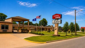 A Country Inn hotel with a clear sky, an American flag, and a signboard advertising amenities like free WiFi and breakfast. - Country Inn Sterling (Sterling)