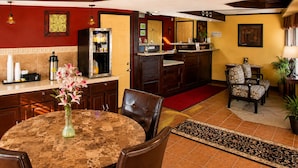 A hotel lobby with a round marble table, leather chairs, a refrigerator, a clock, and a reception desk. - Country Inn Sterling (Sterling)