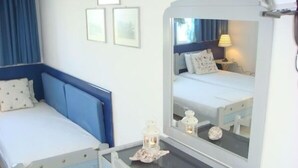 Habitación de hotel con dos camas, un escritorio con teléfono y un espejo que refleja la habitación.
