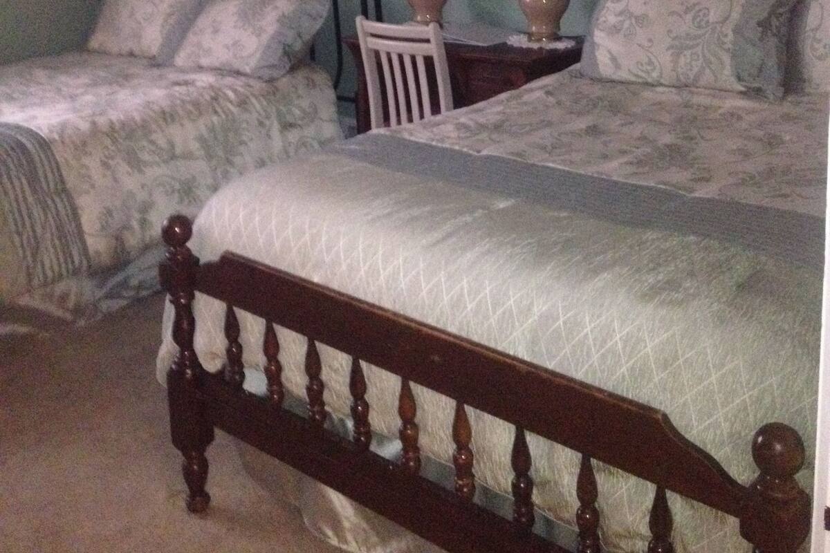 A bedroom with two beds, a chair, and two bedside lamps.