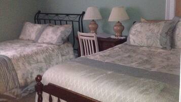A bedroom with two beds, a chair, and two bedside lamps.