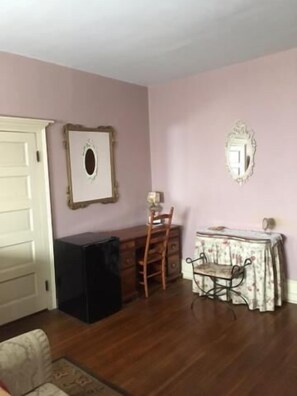 A room with a wooden dresser, a chair, a table with a patterned tablecloth, and a mirror on the wall. - Victorian Charm Inn (Towanda)