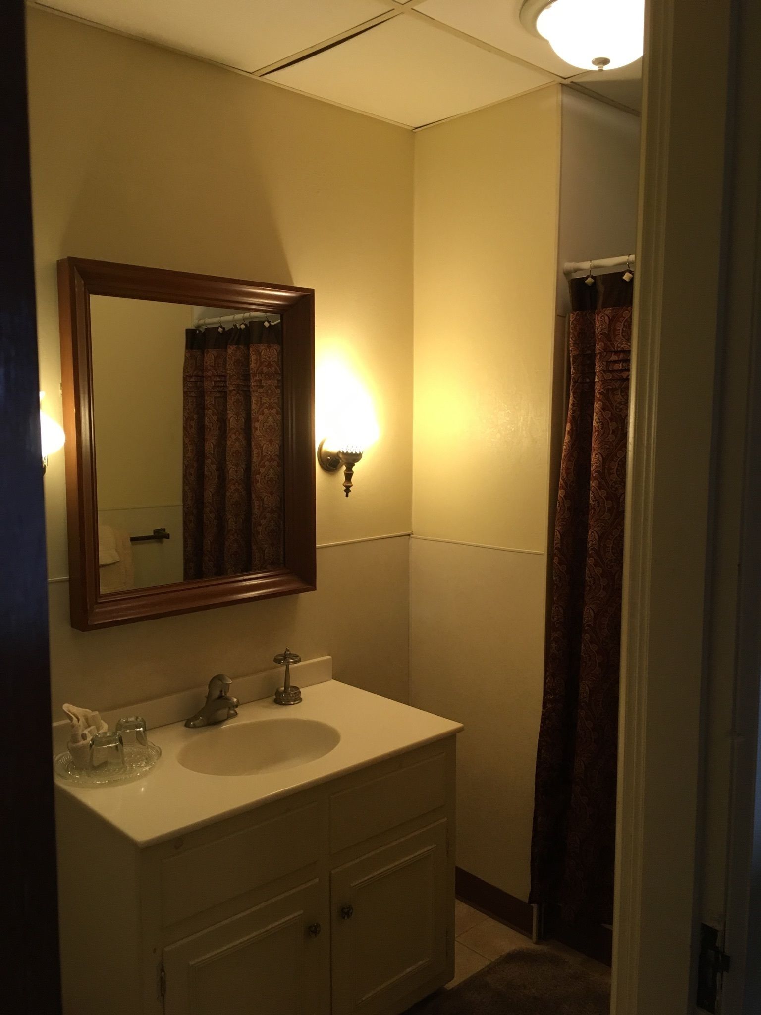 Un baño con lavamanos, espejo y cortina de ducha.