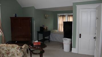 Um quarto com uma cama, cômoda, televisão e lixeira.