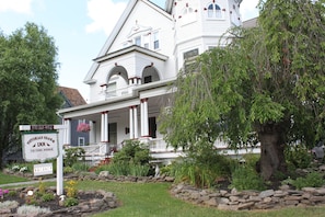 A Victorian Charm Inn with a white facade, multiple balconies, and a stone garden.