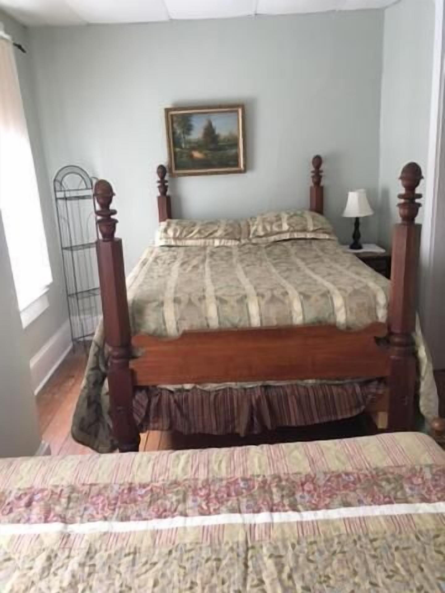 Une chambre à coucher avec un lit en bois, une table de chevet avec une lampe et un tableau accroché au mur.