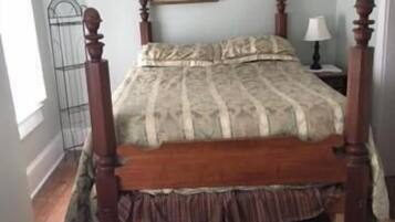 Une chambre à coucher avec un lit en bois, une table de chevet avec une lampe et un tableau accroché au mur.