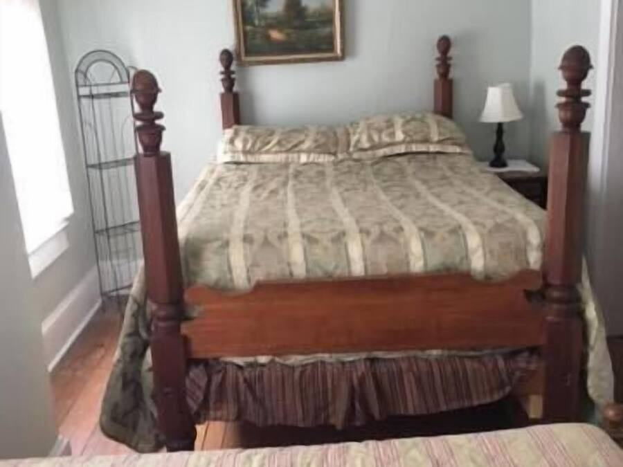 Une chambre à coucher avec un lit en bois, une table de chevet avec une lampe et un tableau accroché au mur.