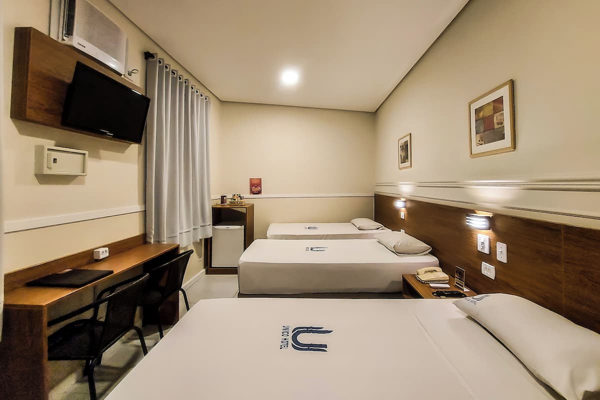 A hotel room with two beds, a desk, a chair, a television, and a small table with a telephone.