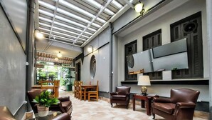 Ein großzügiger Lounge-Bereich mit Ledersofas, einem Couchtisch und einem an der Wand montierten Fernseher.
