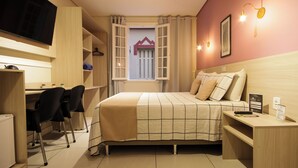 Ein Schlafzimmer mit Bett, Schreibtisch, Stühlen und Fernseher.