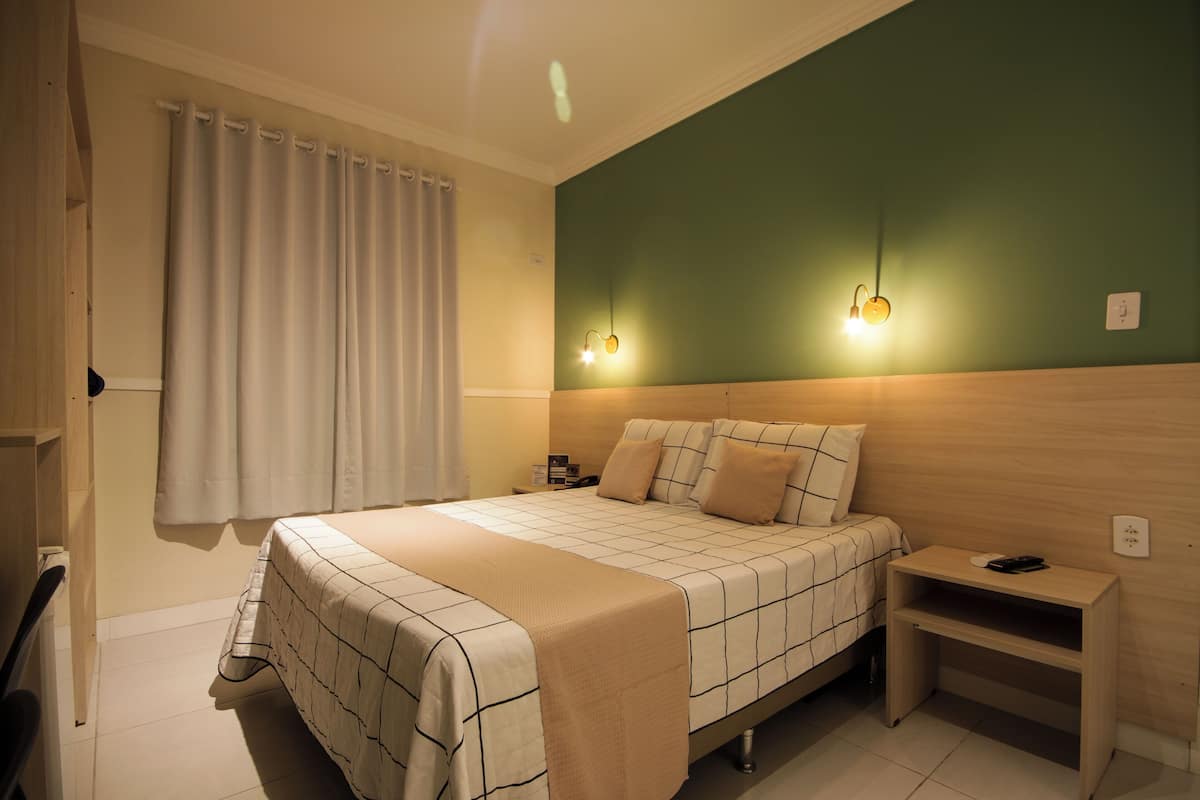 A neatly arranged bedroom with a bed, bedside tables, and a nightstand.