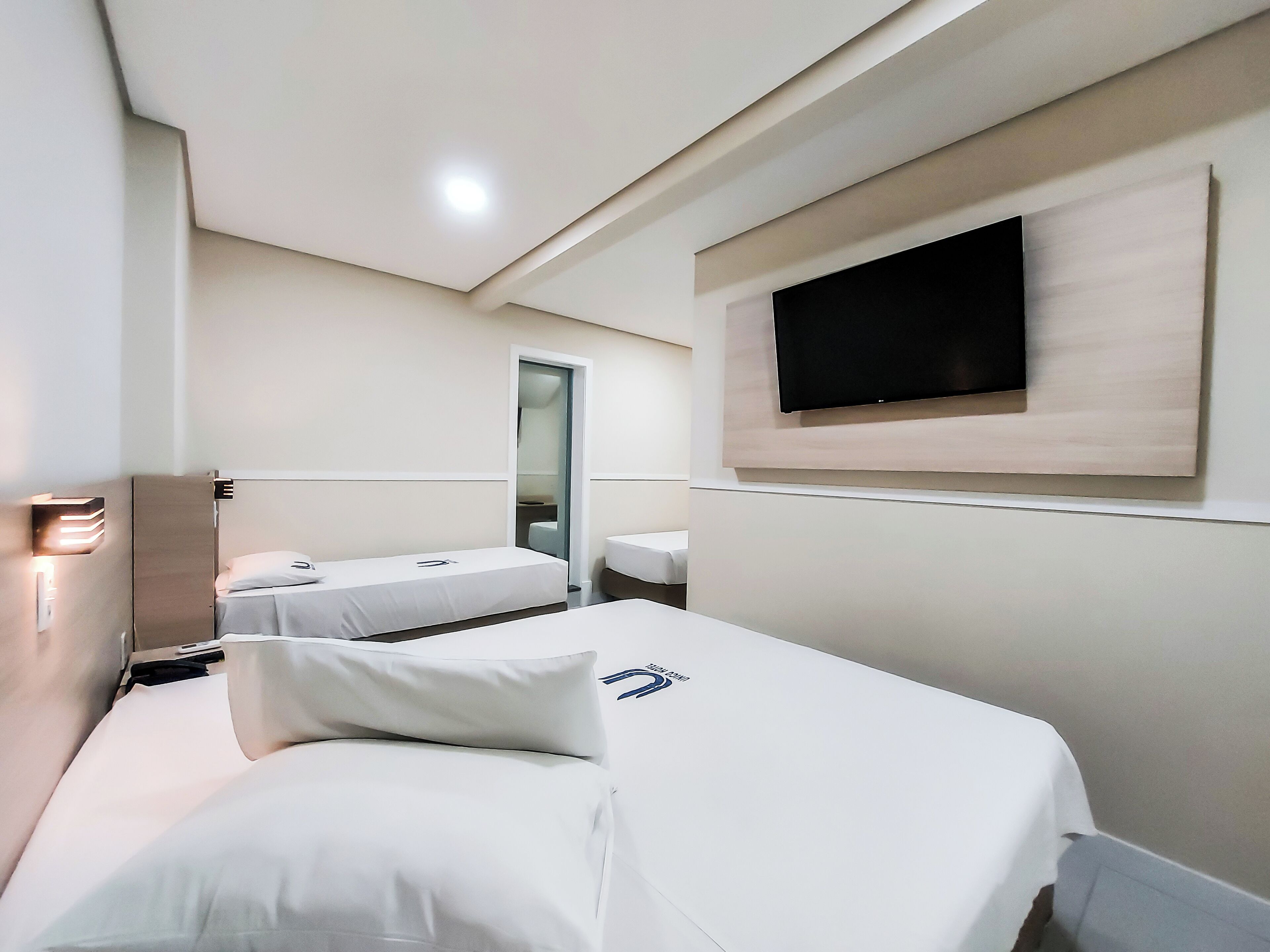 A hotel room with two beds, a TV mounted on the wall, and a mirror.