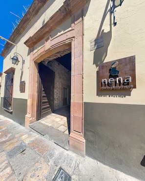 Entrada de un edificio con un cartel que dice 'nena Hotel Boutique'.