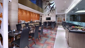 Eine moderne Hotellobby mit Essbereich, einem Buffet und einer großen digitalen Anzeige.