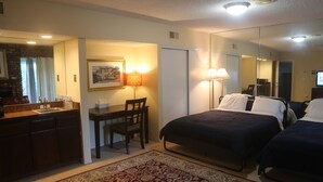 A hotel room with a bed, a desk, a chair, a mirror, and a rug. - Bed and Breakfast in Hollywood Hills (Los Angeles)