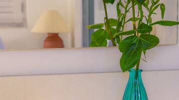 A bathroom sink with a mirror, a teal vase with roses, and a small basket with toiletries.