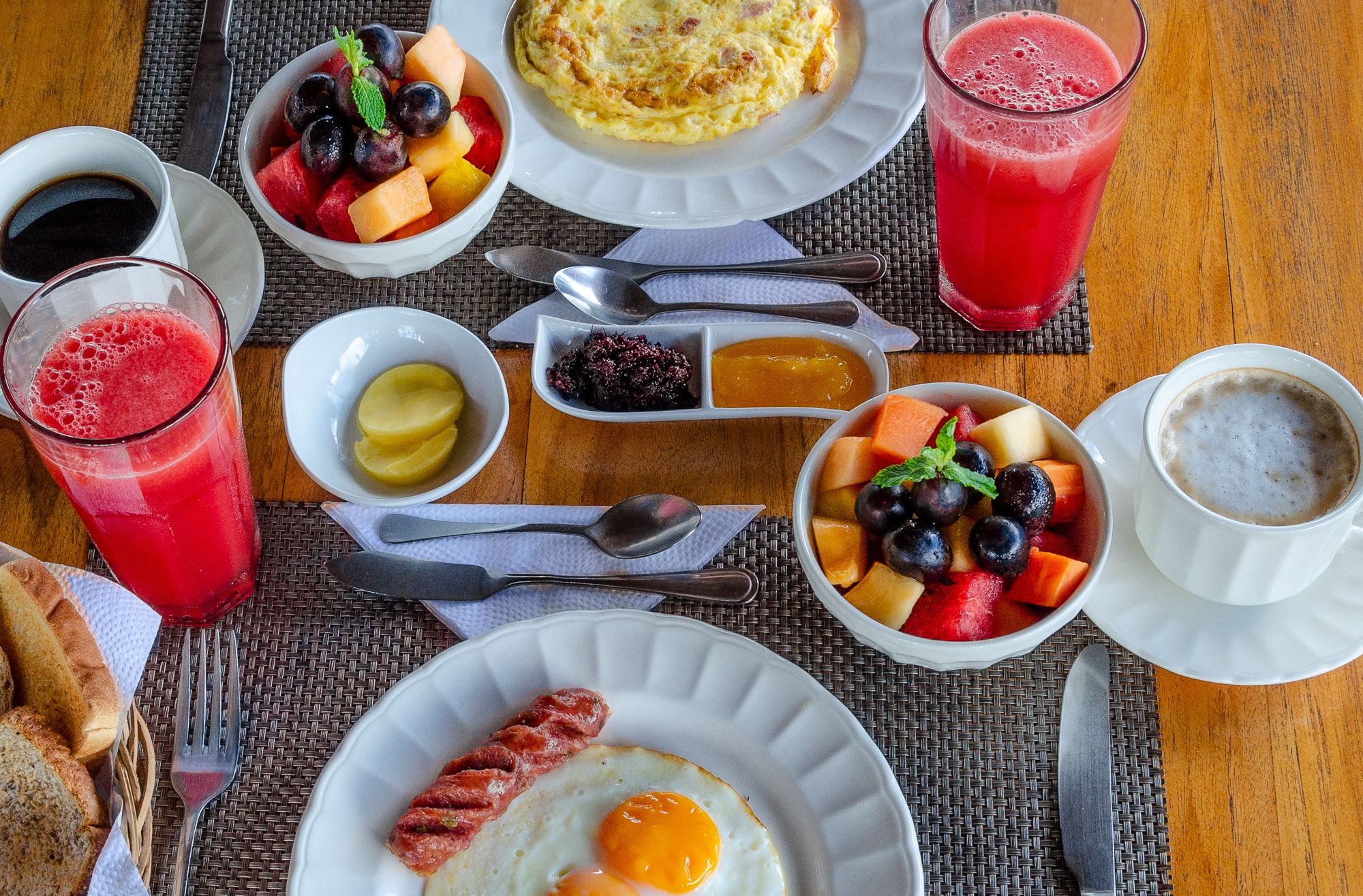 A breakfast setting with various dishes including eggs, sausages, and fruit.